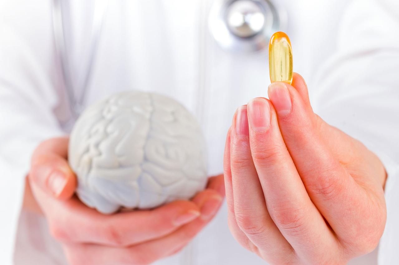 A doctor holds a pill and a plastic model of the human brain.