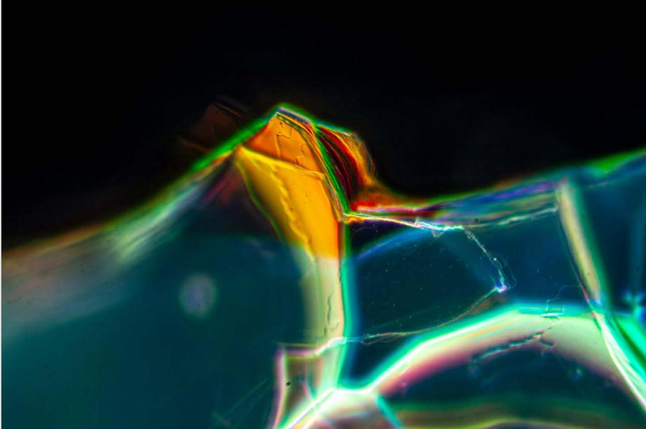 An extreme closeup of a piece of glass with multiple colors. Tufts researchers reveal how photonic crystals were created on a piece of ancient Roman glass by corrosion and crystallization over centuries.
