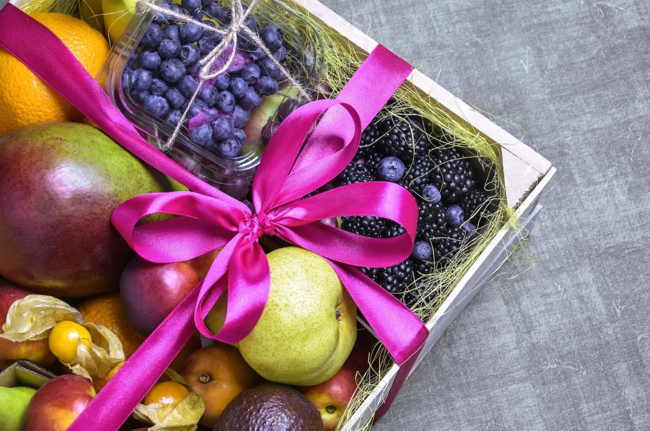 A box with blueberries, blackberries, and other fruits tied with a pink ribbon