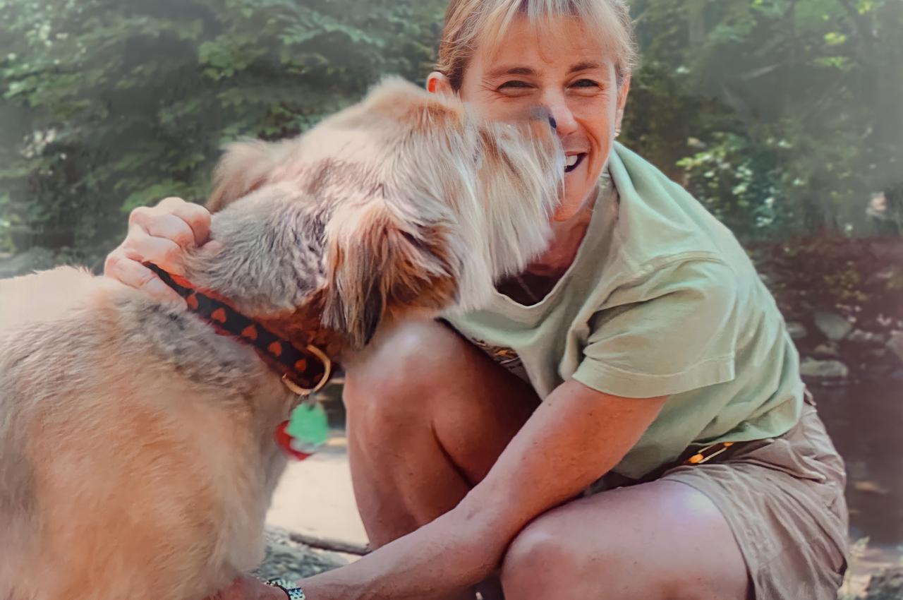 A dog and a smiling woman touch noses